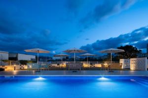 una piscina con sombrillas, mesas y sillas en ネストホテル石垣マエサトビーチ en Isla Ishigaki