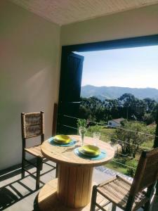mesa con 2 sillas y ventana grande en Montanha Home en Monte Verde