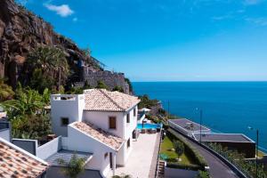 a house on the side of a mountain with the ocean at GALVÃO HOUSE EXPERIENCE in Ribeira Brava