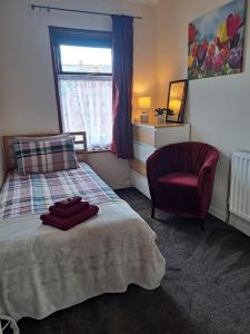 ein Schlafzimmer mit einem Bett, einem Stuhl und einem Fenster in der Unterkunft Nina's Cozy Lodge in Wigan