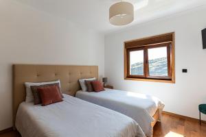 two beds in a white room with a window at GALVÃO HOUSE EXPERIENCE in Ribeira Brava