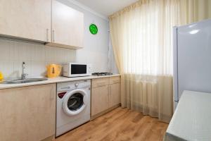 a kitchen with a washing machine and a microwave at Nadezhda Apartment on Abay Avenue 59 in Almaty