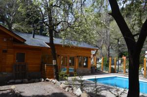 a log cabin with a swimming pool next to a house at Apart Hotel Robles del Sur in San Martín de los Andes
