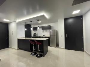 a kitchen with black cabinets and a counter with stools at ItsaHome Apartments - Torre Aqua in Quito