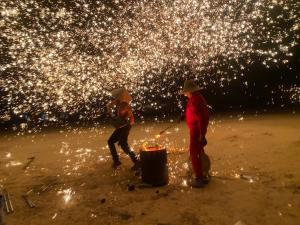 two people standing on a beach with a fire pit at KaoShan Tent Zhangye in Zhangye
