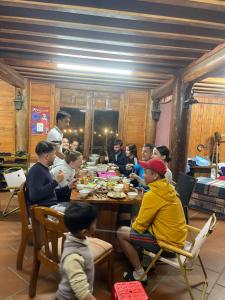 Un groupe de personnes assises autour d'une table à manger dans l'établissement Pea homestay, à Sa Pa