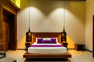 ein Schlafzimmer mit einem großen Bett mit lila Kissen in der Unterkunft Casa de la Luz Hotel Boutique in Mexiko-Stadt