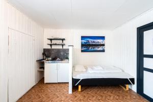 a small white room with a bed and a kitchen at Lydersen Rorbuer Budget Hostel & Private Apartments in Fredvang +145 photos