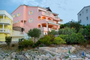 a pink building next to two white buildings at Apartments by the sea Razanj, Rogoznica - 2970 in Rogoznica