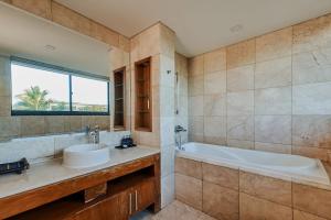 a bathroom with a sink and a tub and a window at Golden Beachside Resort Danang in Da Nang