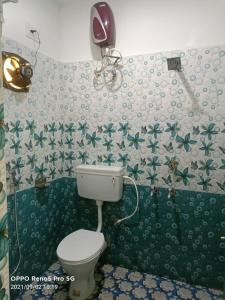 a bathroom with a toilet and green and white wallpaper at OYO Mahavir Guest House in Cuttack