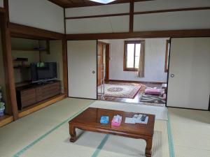 民泊サライ七城 في Kutami: غرفة معيشة مع طاولة قهوة وتلفزيون