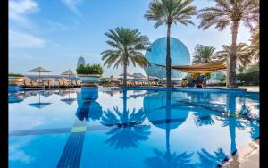 アブダビにあるAl Raha Beach Hotel - Deluxe Gulf Room SGL - UAEのヤシの木とアオクのある大型スイミングプール