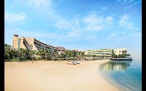 阿布達比的住宿－Al Raha Beach Hotel - Deluxe Gulf Room SGL - UAE，一片拥有部分建筑的海滩,水面和冰 ⁇ 