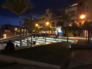 a group of people sitting around a fountain at night at Apartamento en Victoria Park Playa San Juan in Playa de San Juan