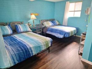 2 camas en una habitación con paredes azules en Lake Point Motel en Marblehead