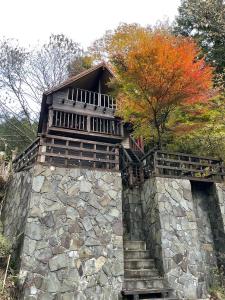 um edifício sobre uma parede de pedra com uma árvore em モリソンヴィラ 石垣のログハウス em Shiso
