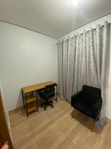 een bureau en een stoel in een kamer met een raam bij Edifício Gervásio in Goiânia