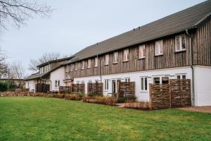 ein großes weißes Gebäude mit einem schwarzen Dach in der Unterkunft Ferienanlage Landliebe Appartement 5 in Alkersum