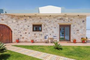 a stone building with a patio with a table and chairs at Dream Sea House villa Falassarna in Falasarna