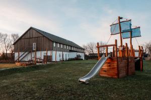 einen Spielplatz mit Rutsche vor einer Scheune in der Unterkunft Ferienanlage Landliebe Ferienhausteil 15 in Alkersum