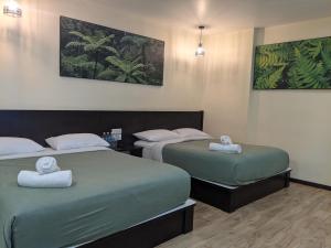 two beds in a hotel room with towels at Hillview Inn Cameron Highlands PROMO in Tanah Rata