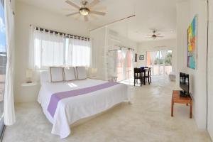 a white bedroom with a large bed and a living room at Villas Geminis Boutique Condohotel in Tulum