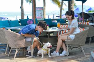 un garçon et une fille assis à une table avec un chien dans l'établissement Anantasila Beach Resort Hua Hin, à Hua Hin