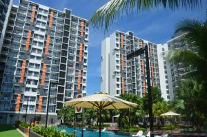 an umbrella in front of two tall buildings at Munchkin Seafront Residence bossku in Kuantan