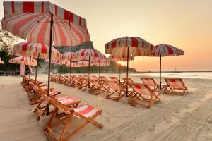 a group of chairs and umbrellas on a beach at Anantasila Beach Resort Hua Hin in Hua Hin