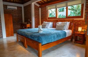 een slaapkamer met een bed met een blauw dekbed en 2 ramen bij Kampung Uma Dawa Villas and Spa in Ubud