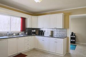 a white kitchen with white cabinets and a window at The Cardinal Cape in High Point