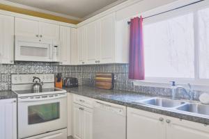 a kitchen with white cabinets and a sink and a window at The Cardinal Cape in High Point