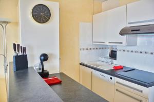 a kitchen with a clock on the wall and a sink at Lovely 51 m with harbour view in Saint-Cyprien