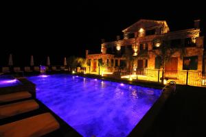 uma piscina com luzes roxas em frente a um edifício em Limni Resort em Ksamil