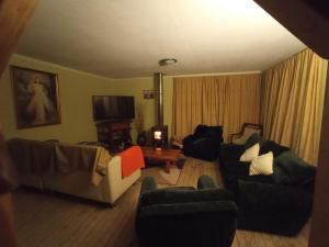 ein Wohnzimmer mit Sofas und Stühlen sowie einem TV in der Unterkunft Casa Lago Rapel in Llallauquén