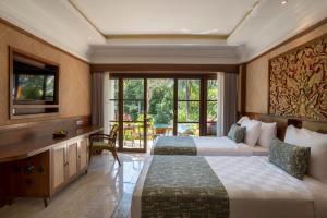 a hotel room with two beds and a television at Arkamara Dijiwa Ubud in Ubud