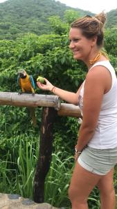 a woman standing next to a parrot on a fence at HOSTAL MIRADOR dentro del parque tayrona in El Zaino