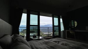 1 dormitorio con cama y vistas a un balcón en 茶緣觀舍民宿 en Fanlu