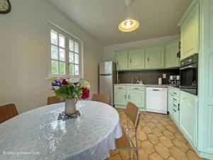 a kitchen with a table with a vase of flowers on it at Maison confortable dans le Perche avec jardin et animaux admis - FR-1-497-205 in Longny-au-Perche