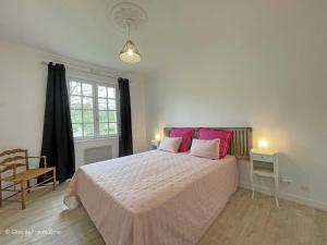a bedroom with a large bed with pink pillows at Maison confortable dans le Perche avec jardin et animaux admis - FR-1-497-205 in Longny-au-Perche