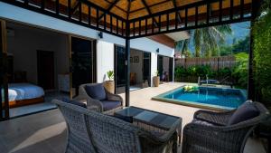 un patio con sedie, tavolo e piscina di Temple villas Koh Phangan a Ko Phangan