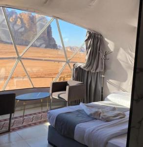 a room with a bed and a large window at RUM ROYAL FLOWER lUXURY CAMP in Wadi Rum