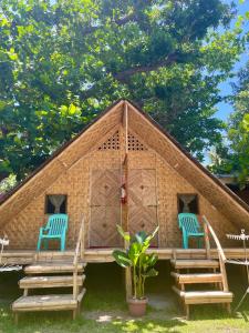 a house with two blue chairs in front of it at Borbon's Treehouse By the Sea in Mambajao