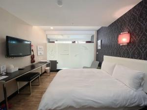 Habitación de hotel con cama, escritorio y TV. en Love River Inn en Kaohsiung