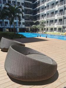 two wicker benches sitting in front of a large building at Shore 3 mall of Asia condotel in Manila