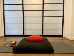 a red pillow and a bowl on a floor with a wall at Fitzroy Zen in Melbourne