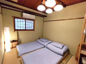 a bedroom with a bed with blue sheets and a light at Hostel Caranashi in Osaka
