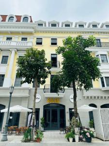 a yellow building with trees in front of it at Soleil Hostel in Ha Long