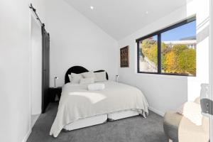 a white bedroom with a bed and a window at Roam Taupo Lakefront Combined Units 1&2 in Taupo